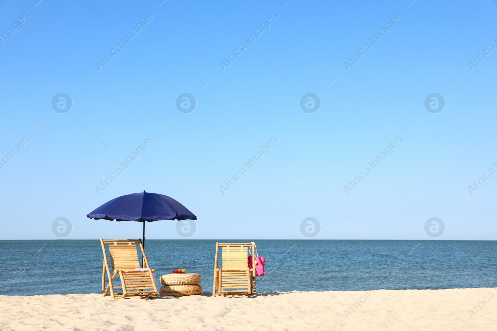 Photo of Empty wooden sunbeds and beach accessories on sandy shore