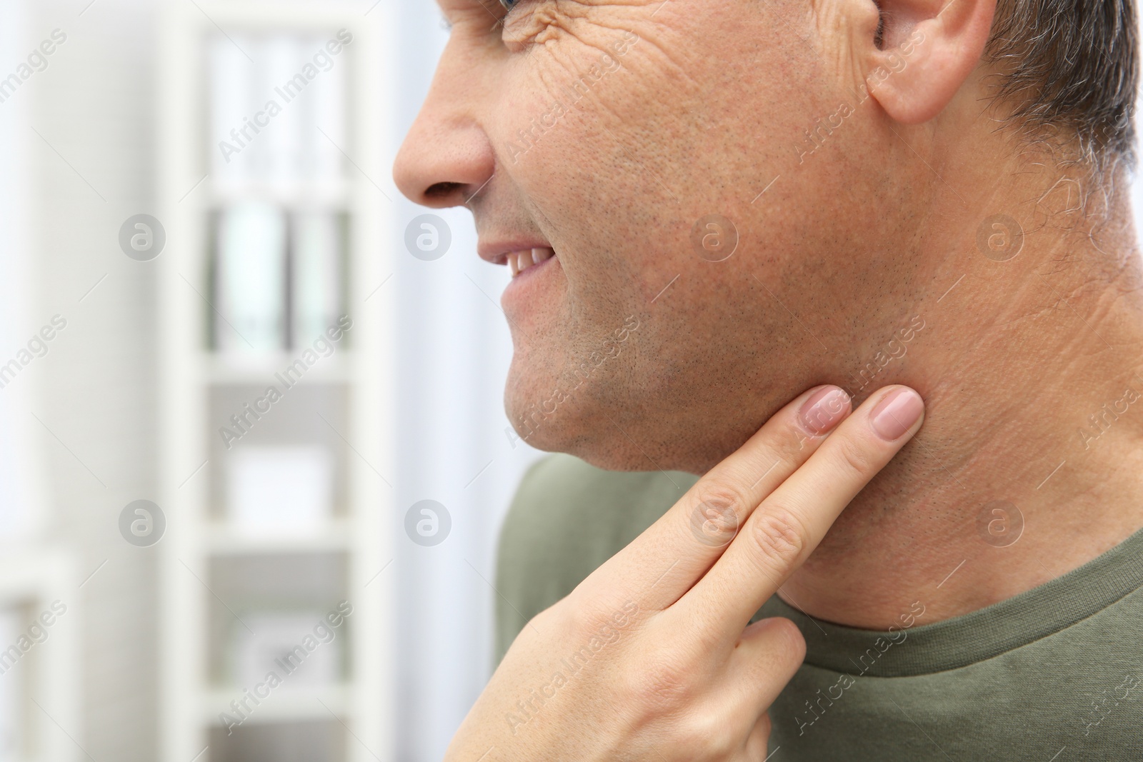 Photo of Young woman checking mature man's pulse with fingers indoors, closeup