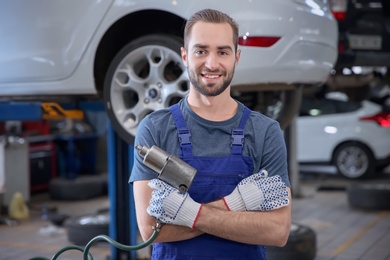 Photo of Young mechanic with torque pistol at tire service