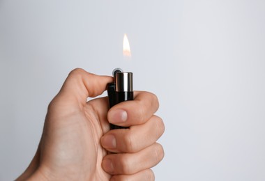 Photo of Woman holding black lighter on white background, closeup