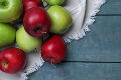 Fresh ripe red and green apples on light blue wooden table, flat lay, Space for text