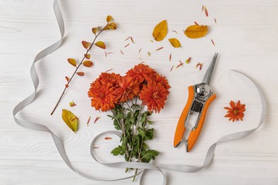 Photo of Flat lay composition with secateurs, ribbon and Chrysanthemum flowers on white wooden table