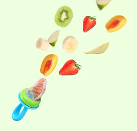 Image of Nibbler and different fruits falling on light background. Baby feeder