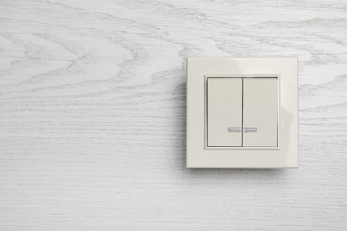 Photo of Modern light switch on white wooden background. Space for text