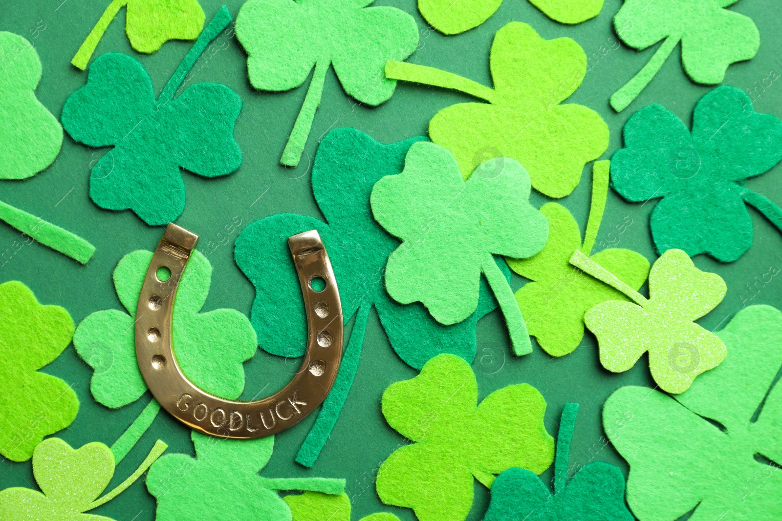 Photo of Flat lay composition with clover leaves and horseshoe on green background. St. Patrick's day