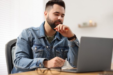 Young man watching webinar at table in room