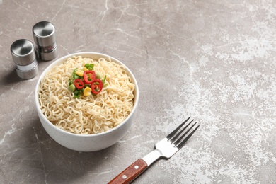 Bowl of noodles with vegetables and fork served on table. Space for text