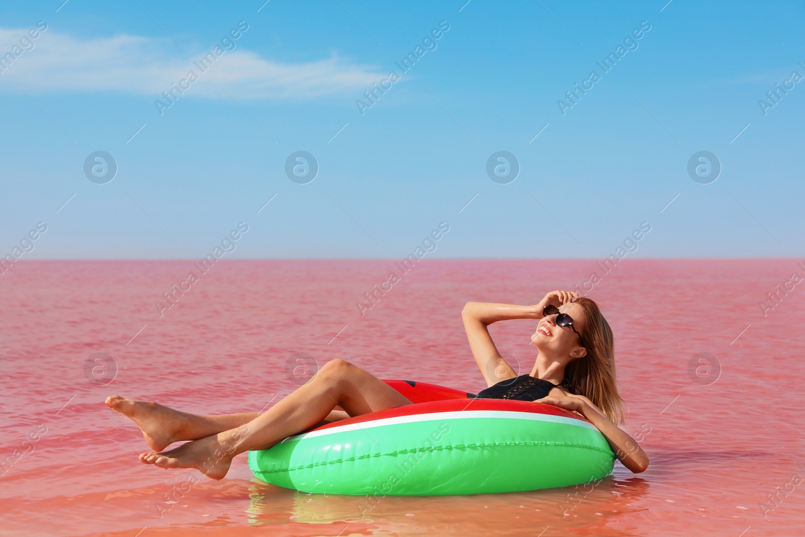 Photo of Beautiful woman on inflatable ring in pink lake