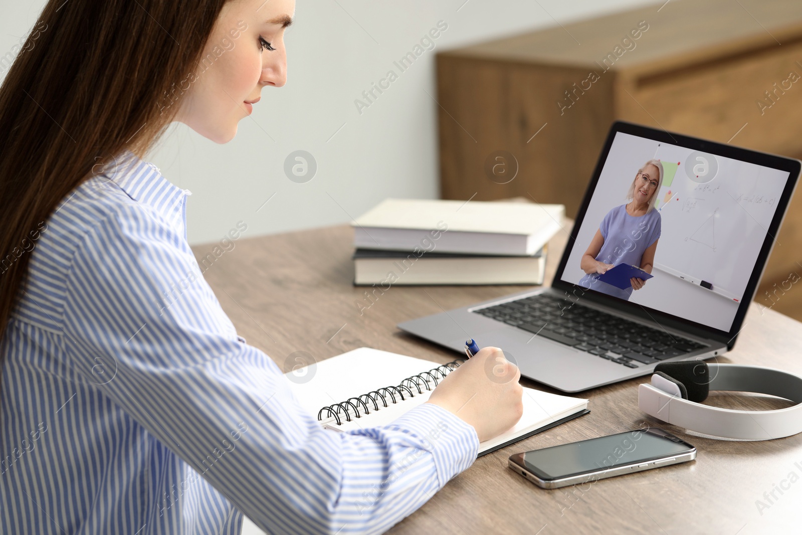 Image of E-learning. Young woman having online lesson with teacher via laptop at home