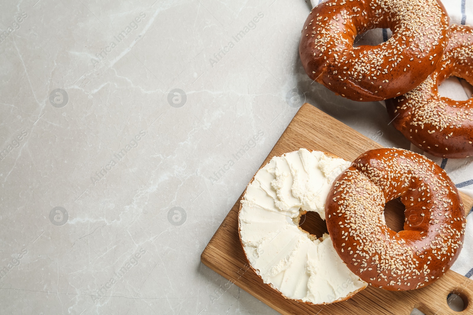 Photo of Delicious bagel with cream cheese on light table, flat lay. Space for text