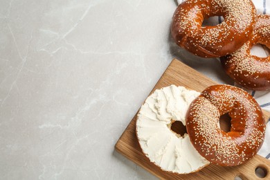 Delicious bagel with cream cheese on light table, flat lay. Space for text