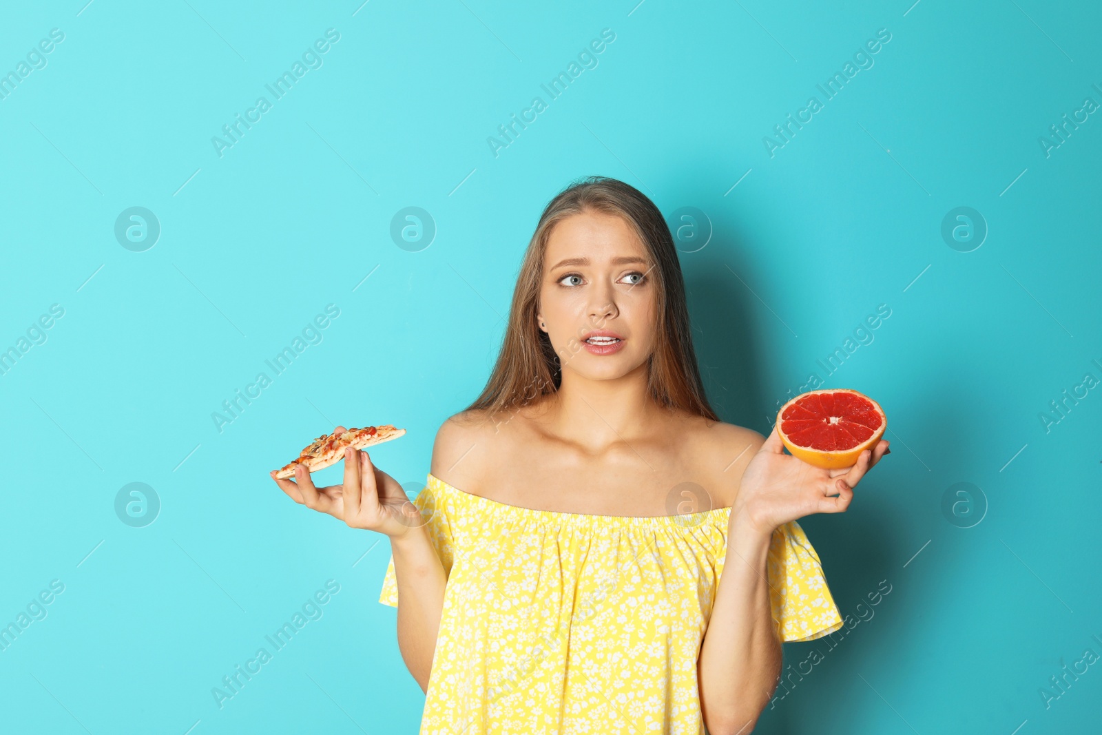 Photo of Young woman with grapefruit and pizza on color background. Healthy diet