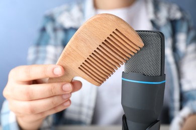 Photo of Woman making ASMR sounds with microphone and wooden comb, closeup