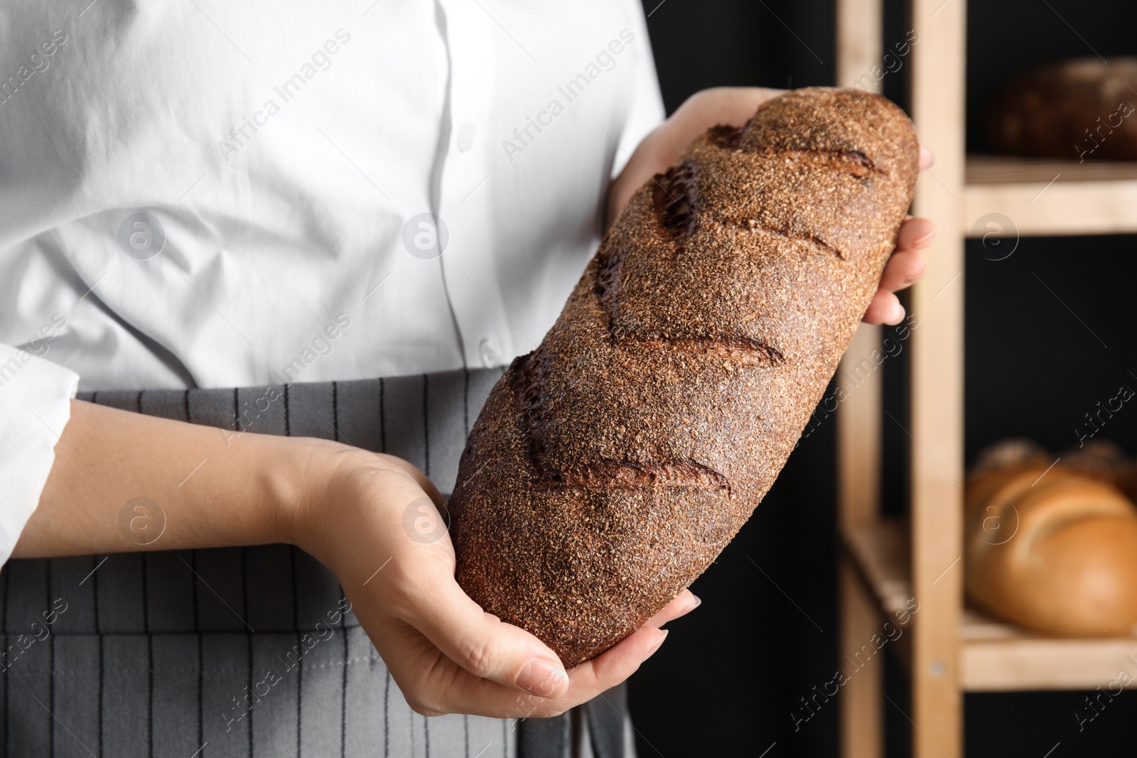 Photo of Baker holding loaf of bread indoors, closeup