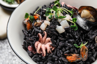 Photo of Delicious black risotto with seafood in bowl on table, closeup