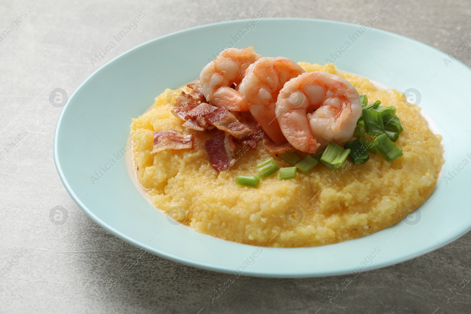 Photo of Plate with fresh tasty shrimps, bacon, grits and green onion on grey table, closeup