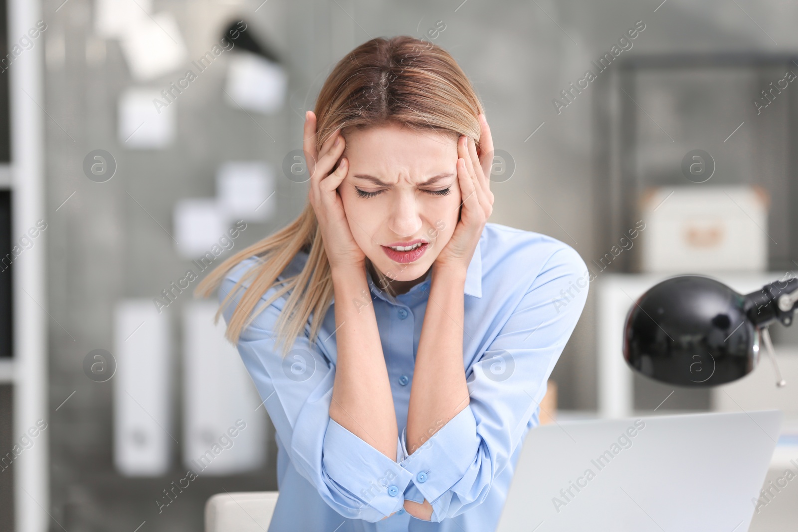 Photo of Young woman suffering from headache in office