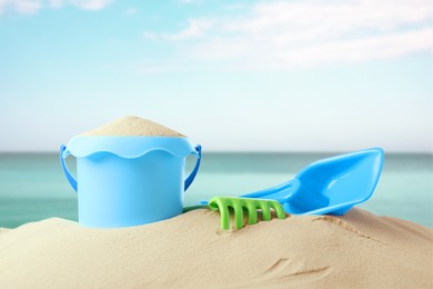 Plastic toy set with shovel on sandy beach near sea