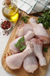 Raw chicken drumsticks and ingredients on white wooden table, flat lay