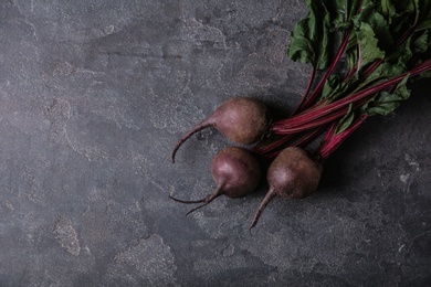 Photo of Fresh beets with leaves on grey table, top view. Space for text