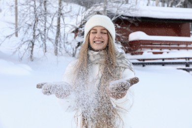 Photo of Winter vacation. Beautiful woman playing with snow outdoors