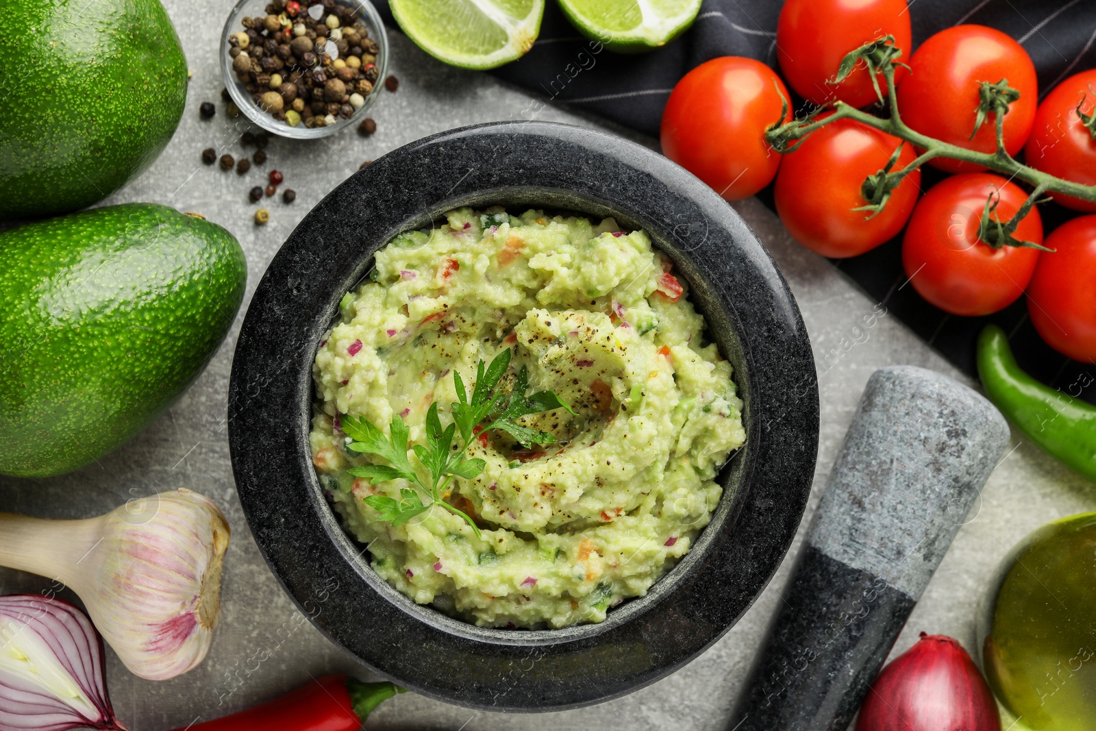 Photo of Delicious guacamole and ingredients on grey table, flat lay