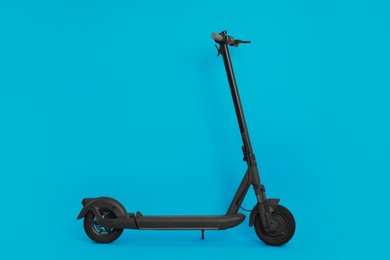 Photo of Modern electric kick scooter on light blue background