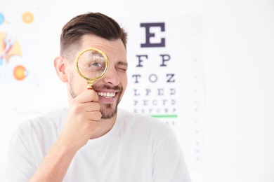 Photo of Young man with magnifier visiting ophthalmologist