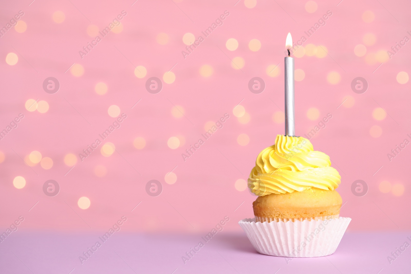 Photo of Birthday cupcake with candle on table against festive lights, space for text