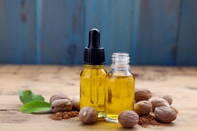 Photo of Bottles of nutmeg oil, nuts and powder on wooden table