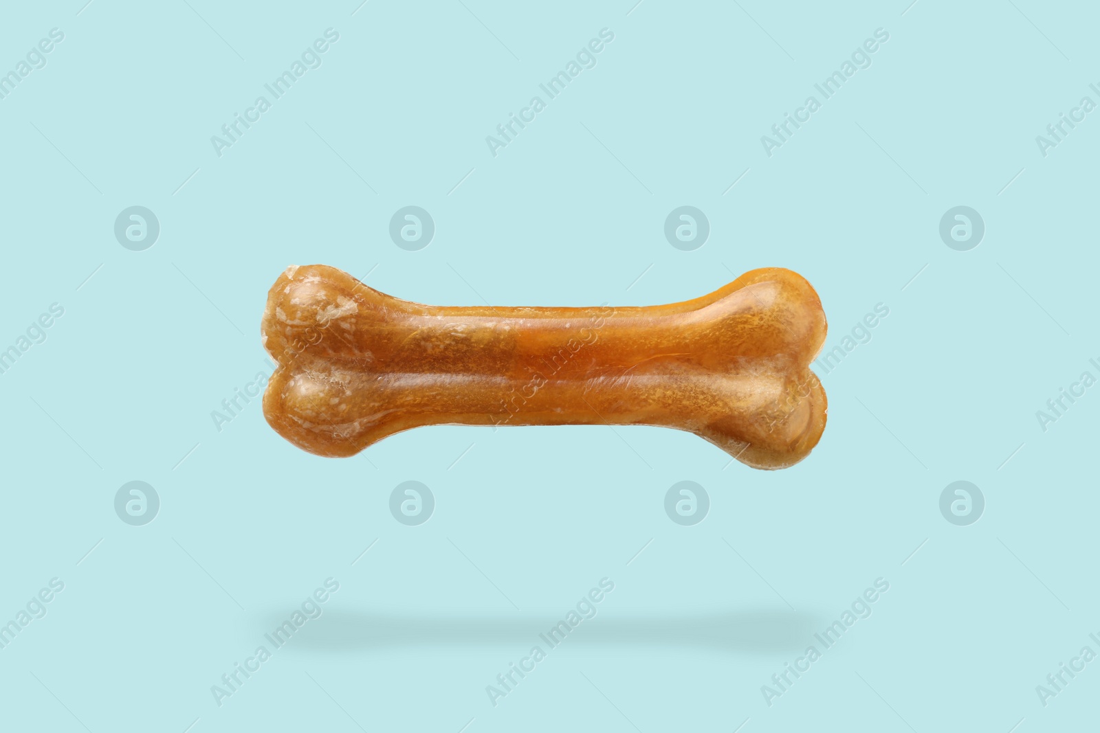 Image of Bone dog treat in air on light blue background
