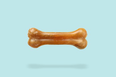 Bone dog treat in air on light blue background