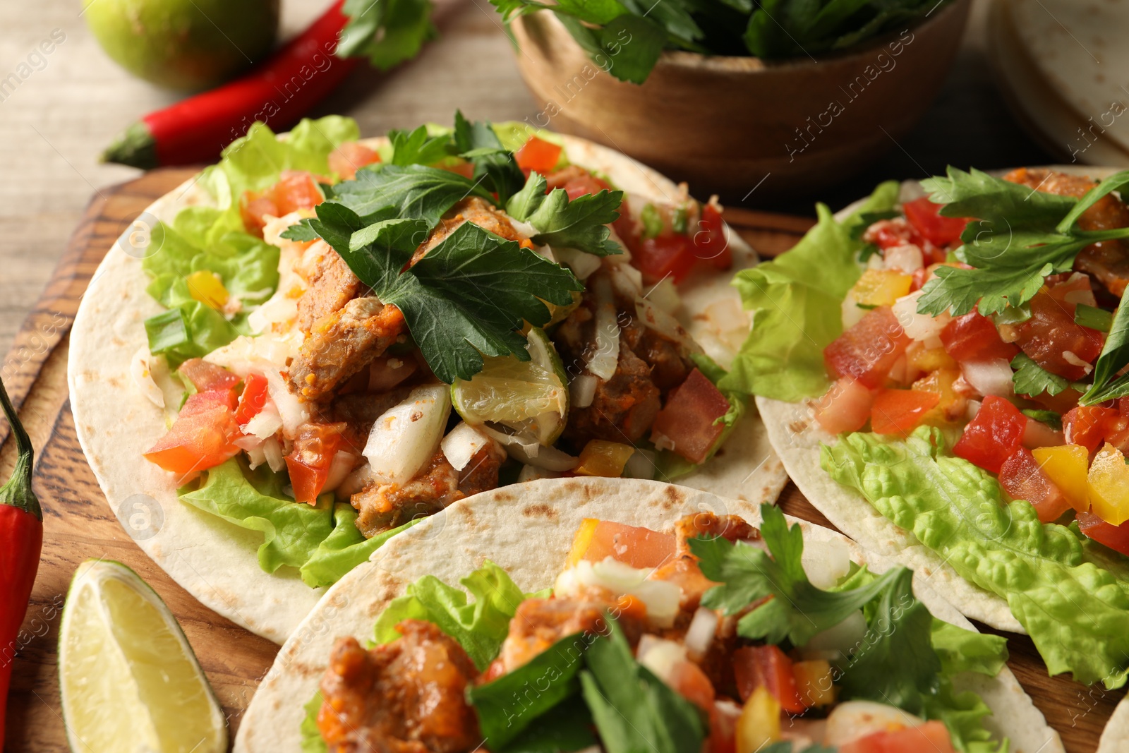 Photo of Delicious tacos with vegetables, meat and lime on table, closeup