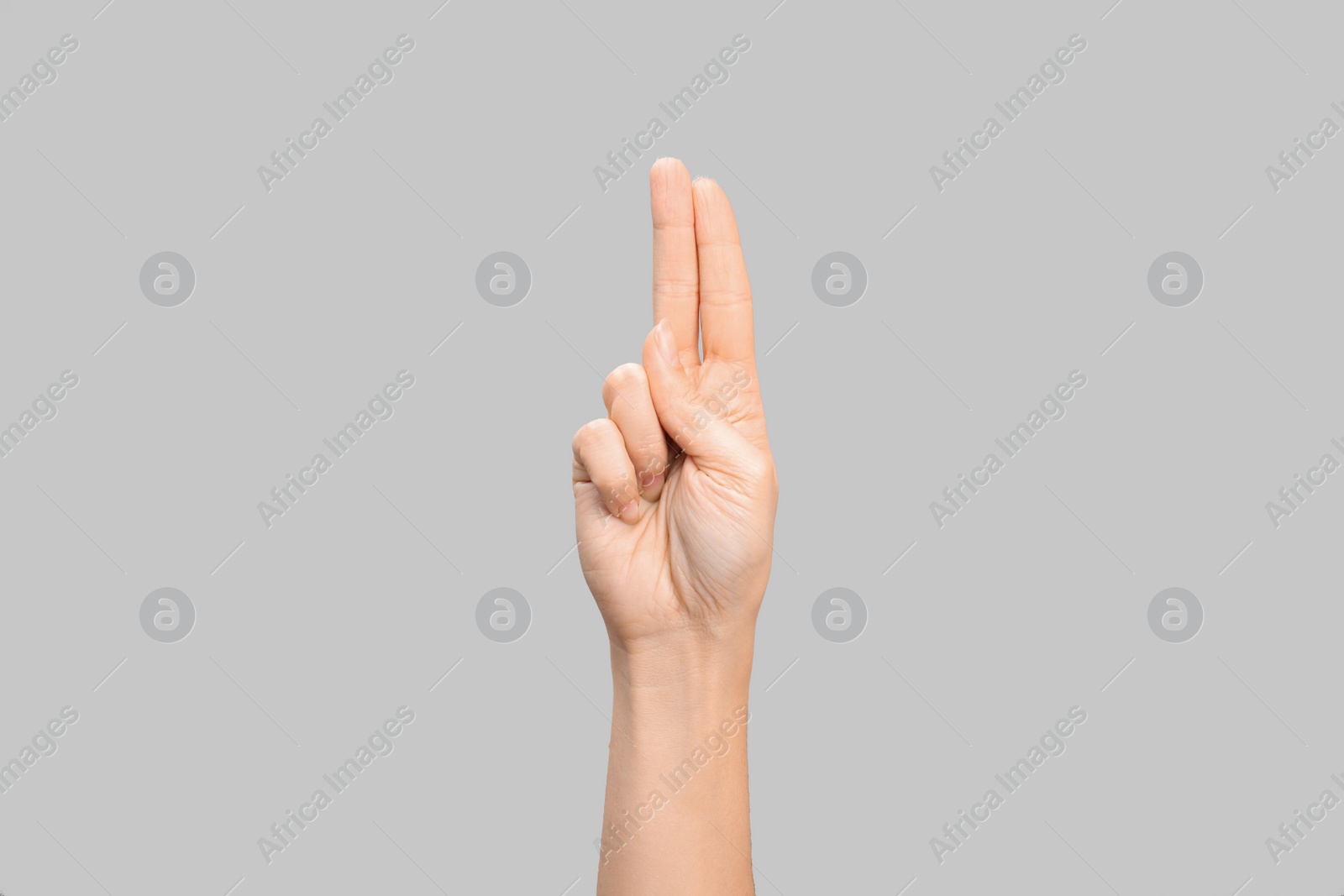 Photo of Woman showing U letter on grey background, closeup. Sign language