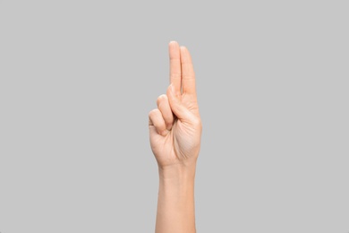 Photo of Woman showing U letter on grey background, closeup. Sign language