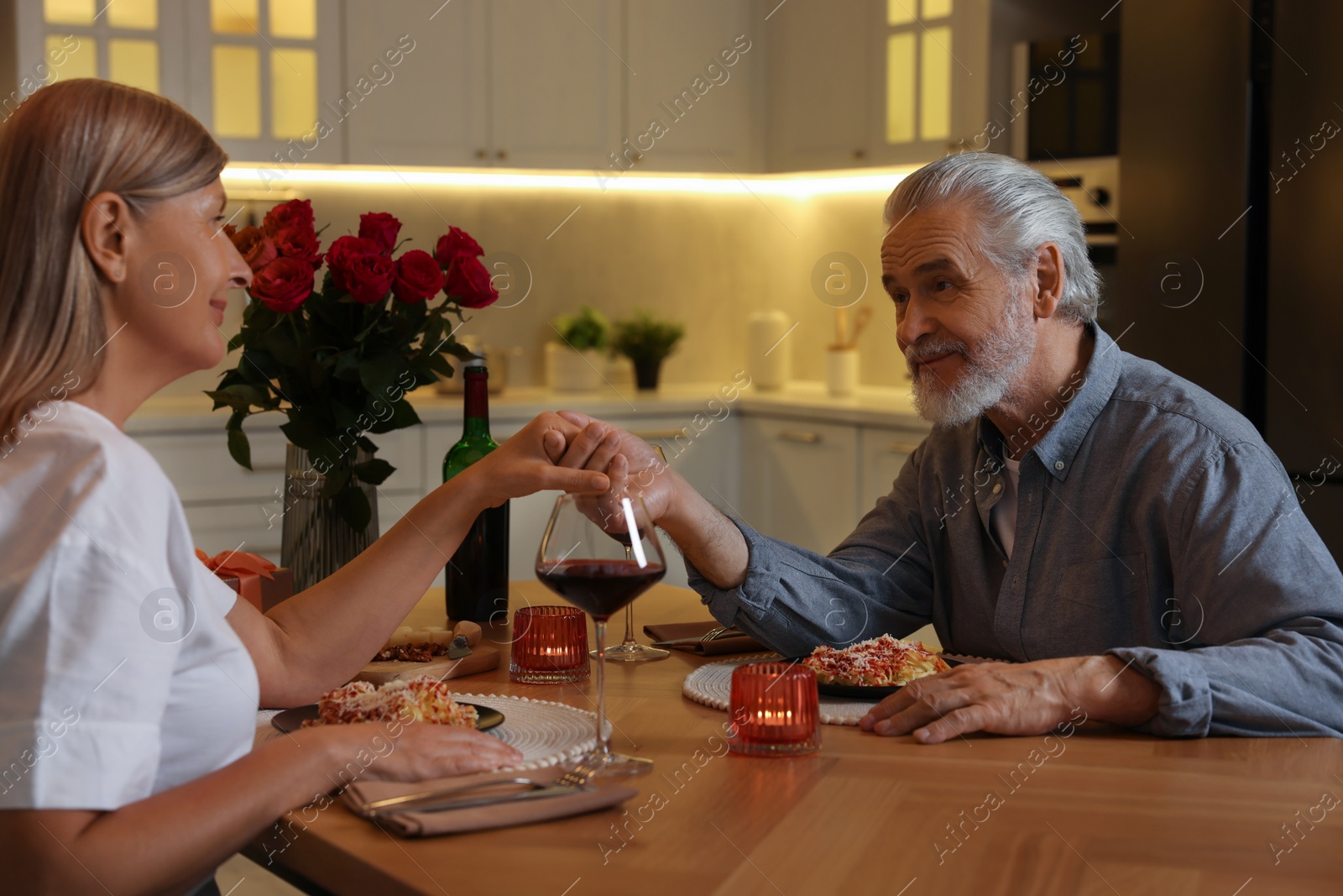 Photo of Affectionate senior couple having romantic dinner at home