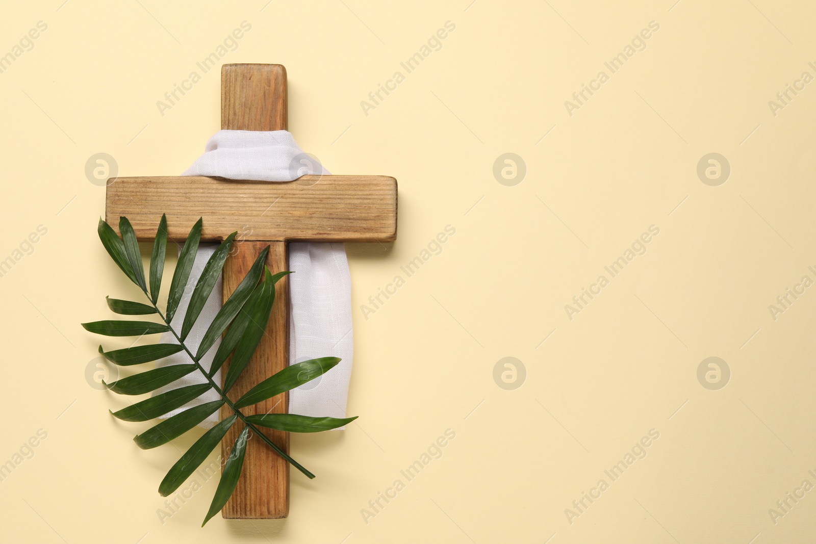 Photo of Wooden cross, white cloth and palm leaf on beige background, top view with space for text. Easter attributes