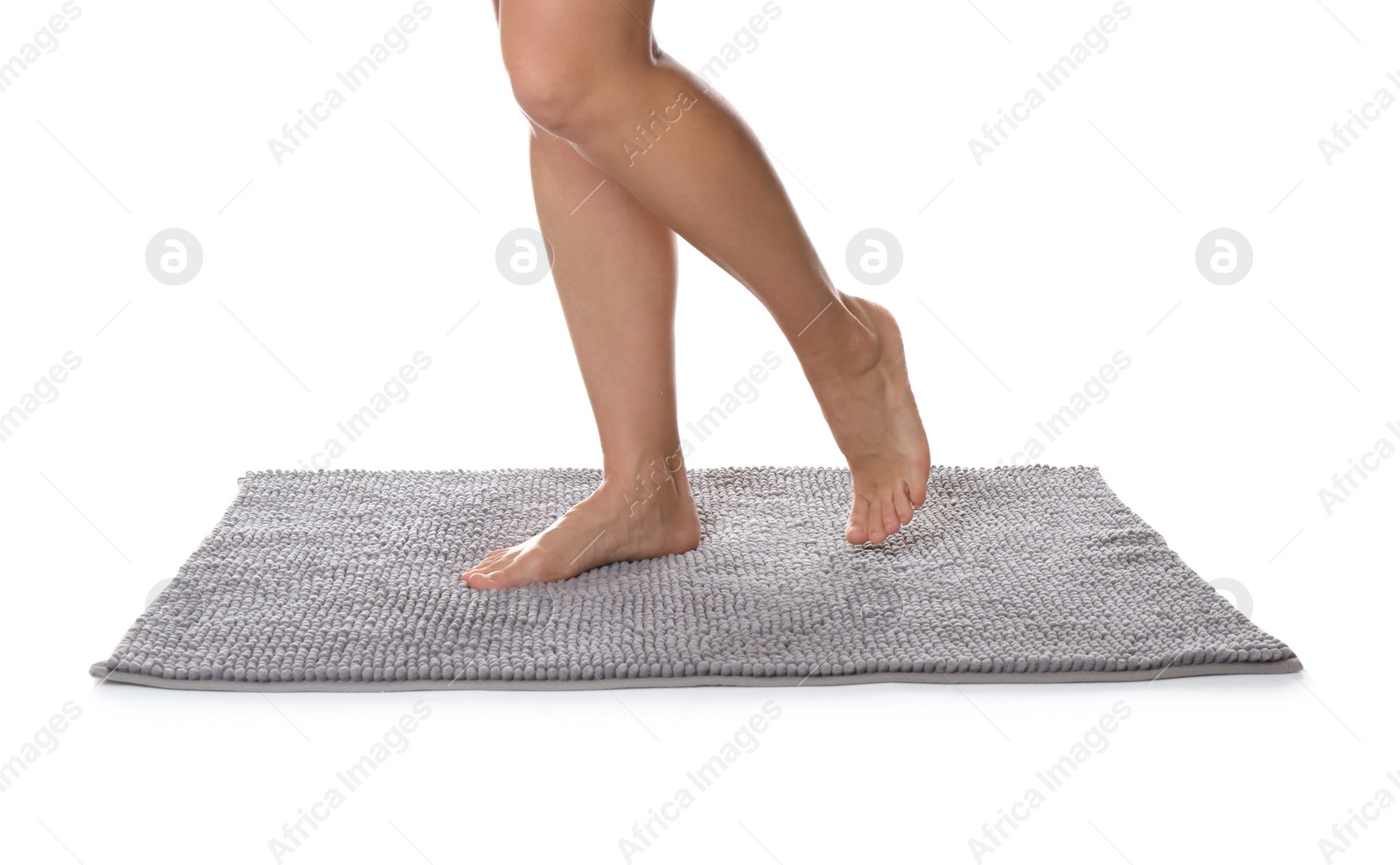 Photo of Woman standing on soft grey bath mat against white background, closeup