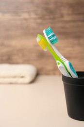 Toothbrushes in holder on blurred background, space for text