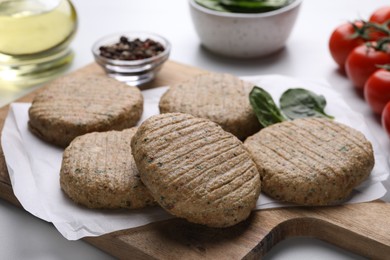 Raw vegan cutlets and different products on white table, closeup