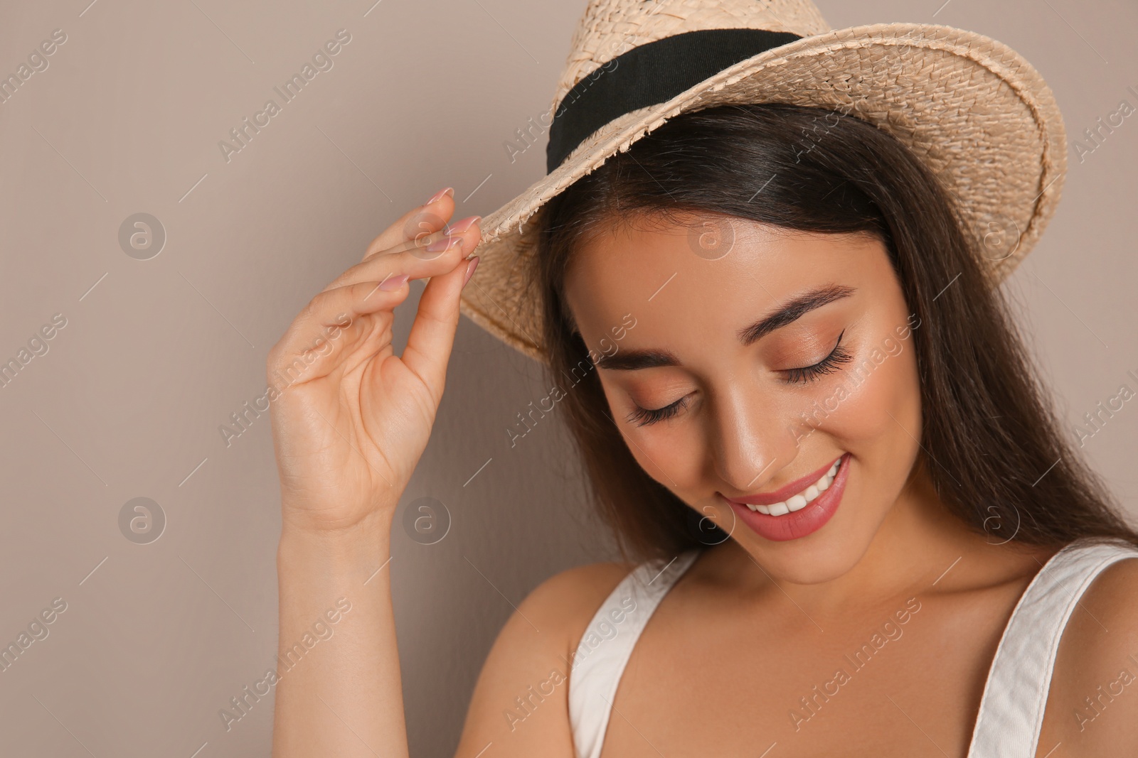 Photo of Beautiful young woman wearing straw hat on beige background. Stylish headdress