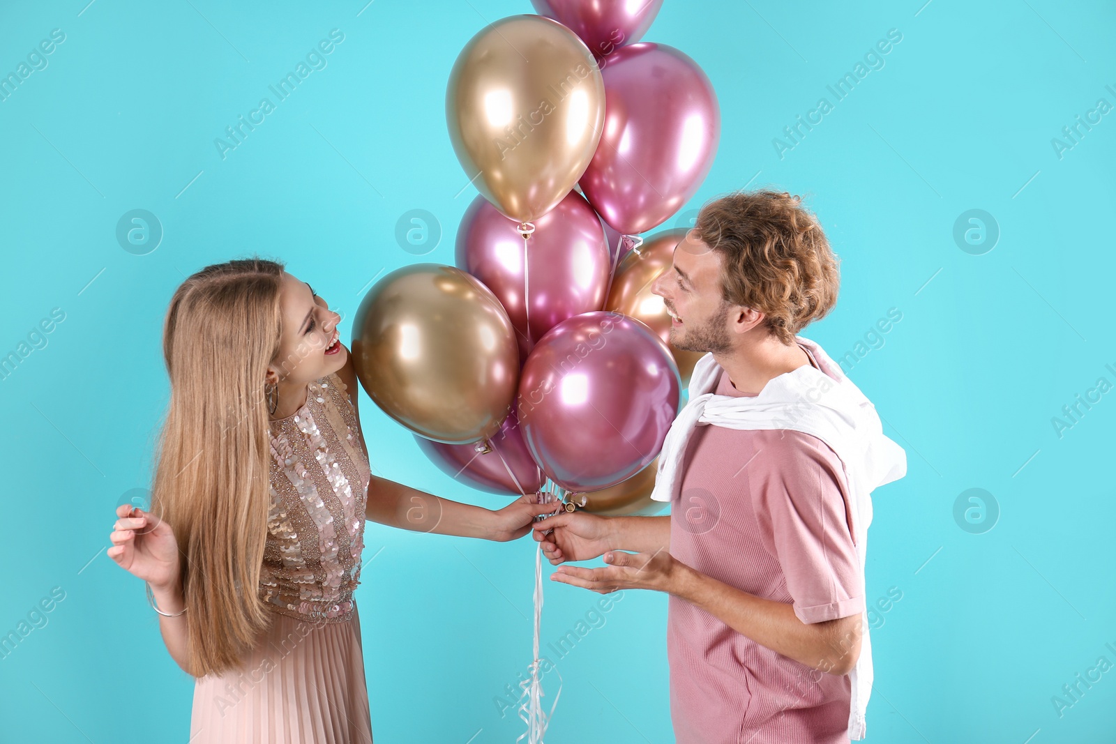 Photo of Young couple with air balloons on color background