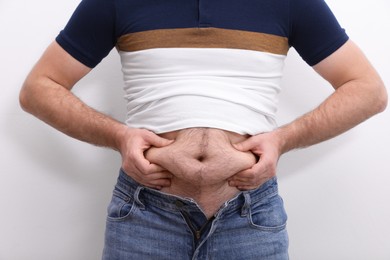 Photo of Man wearing tight t-shirt and jeans on white background, closeup. Overweight problem
