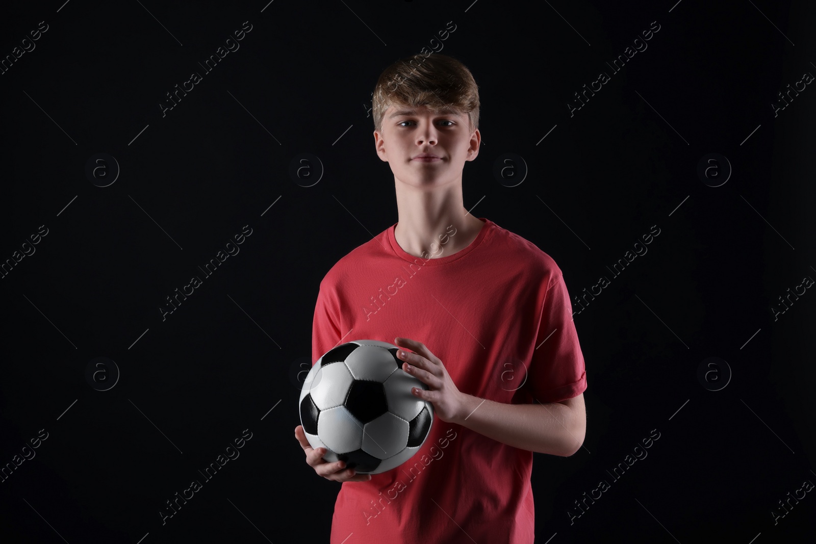 Photo of Teenage boy with soccer ball on black background