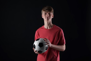 Teenage boy with soccer ball on black background