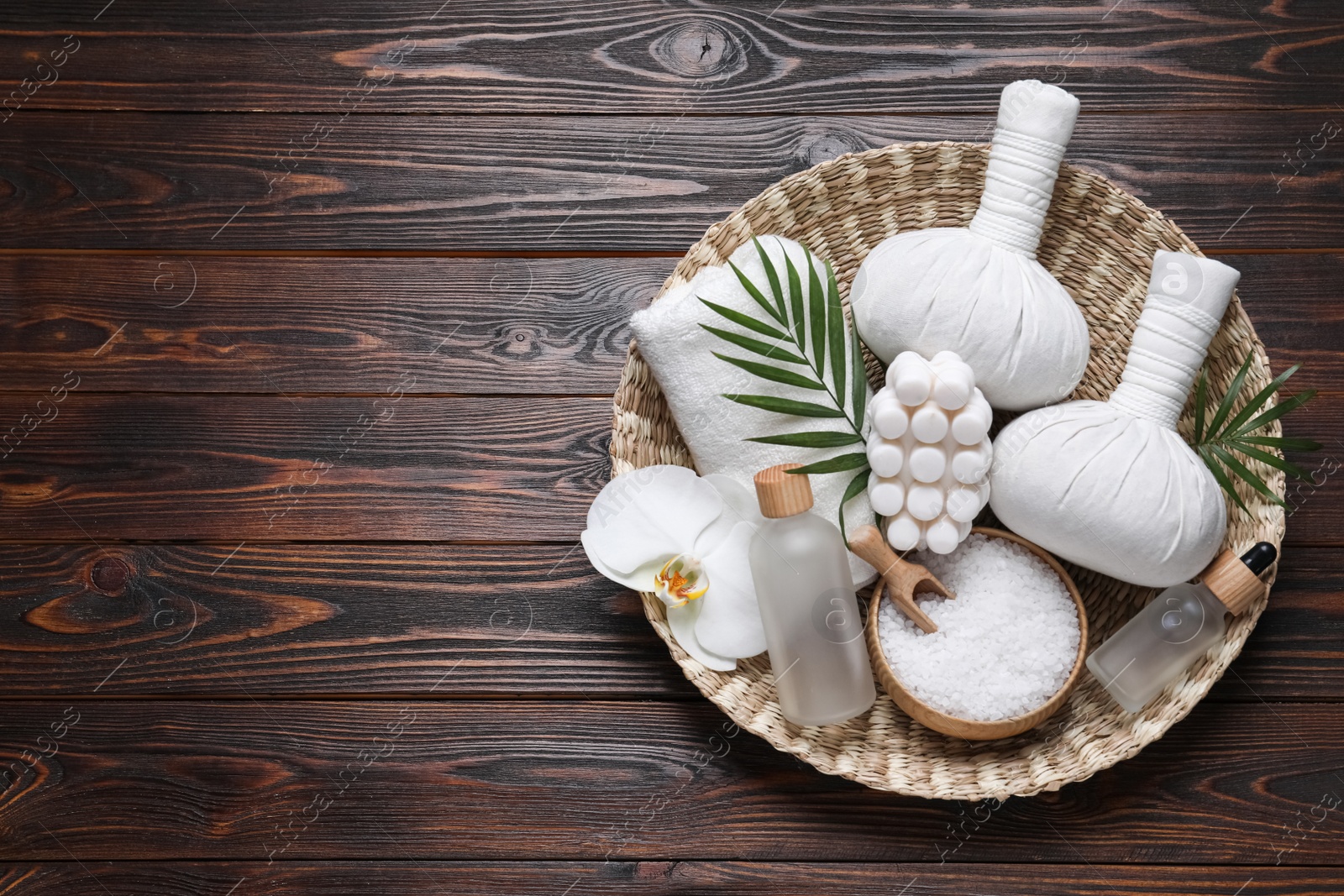 Photo of Composition of herbal bags and spa products on wooden table, top view. Space for text