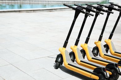Photo of Many modern electric scooters outdoors, space for text. Rental service