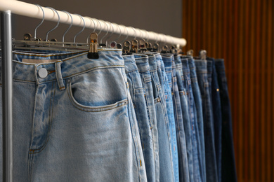 Rack with different stylish jeans, closeup view