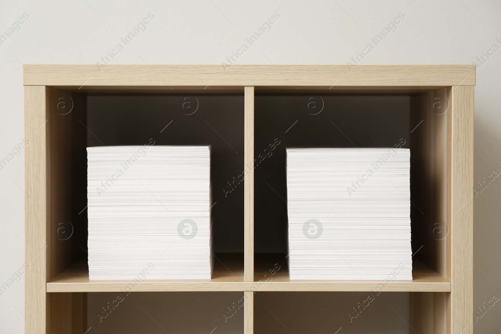 Photo of Stacks of paper sheets on shelves indoors