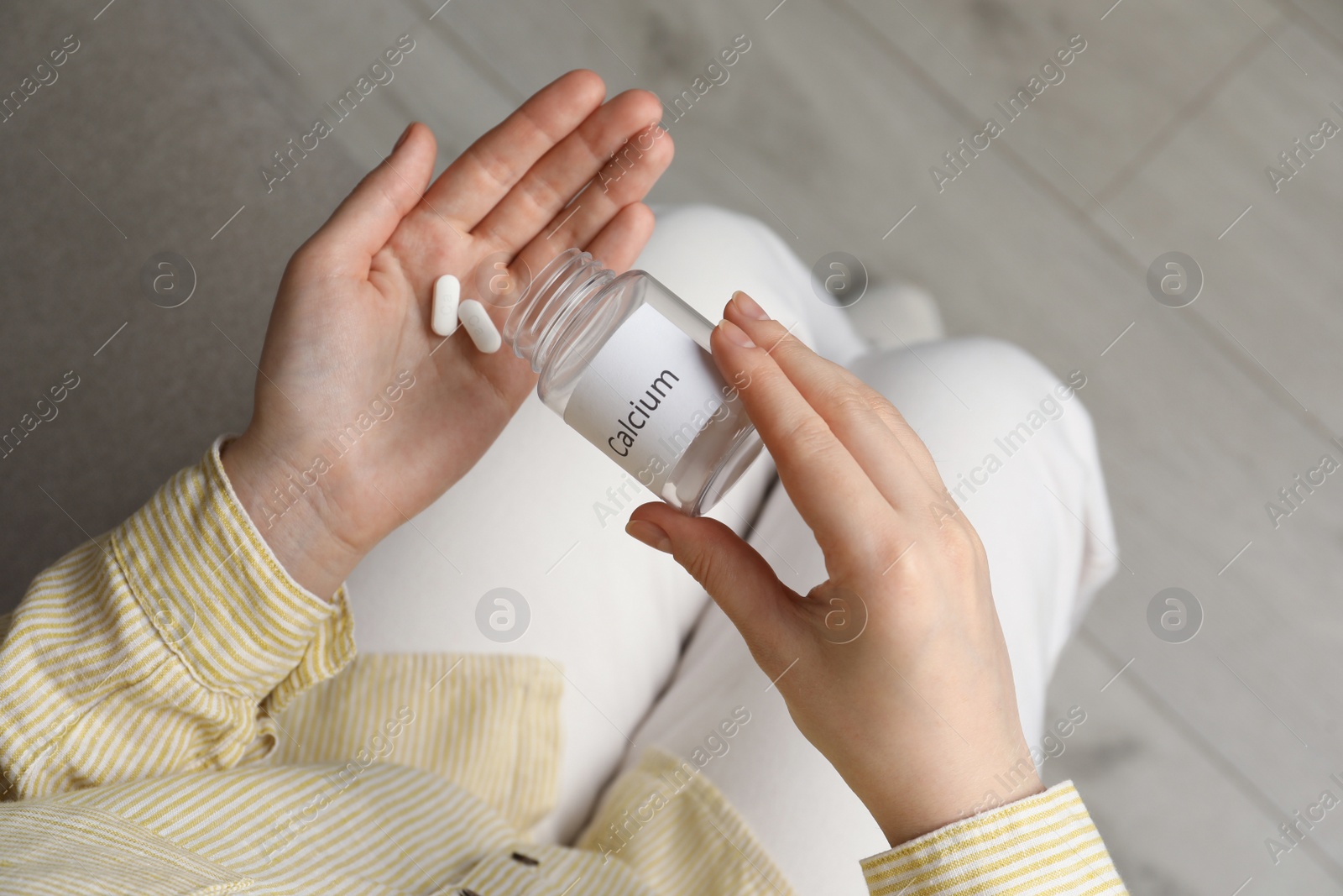 Photo of Calcium supplement. Woman taking pills indoors, top view